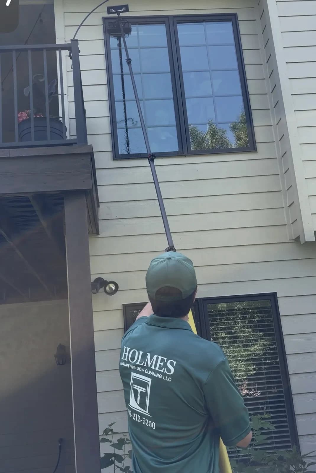 A water-fed pole reaching second-storey glass on an Omaha home